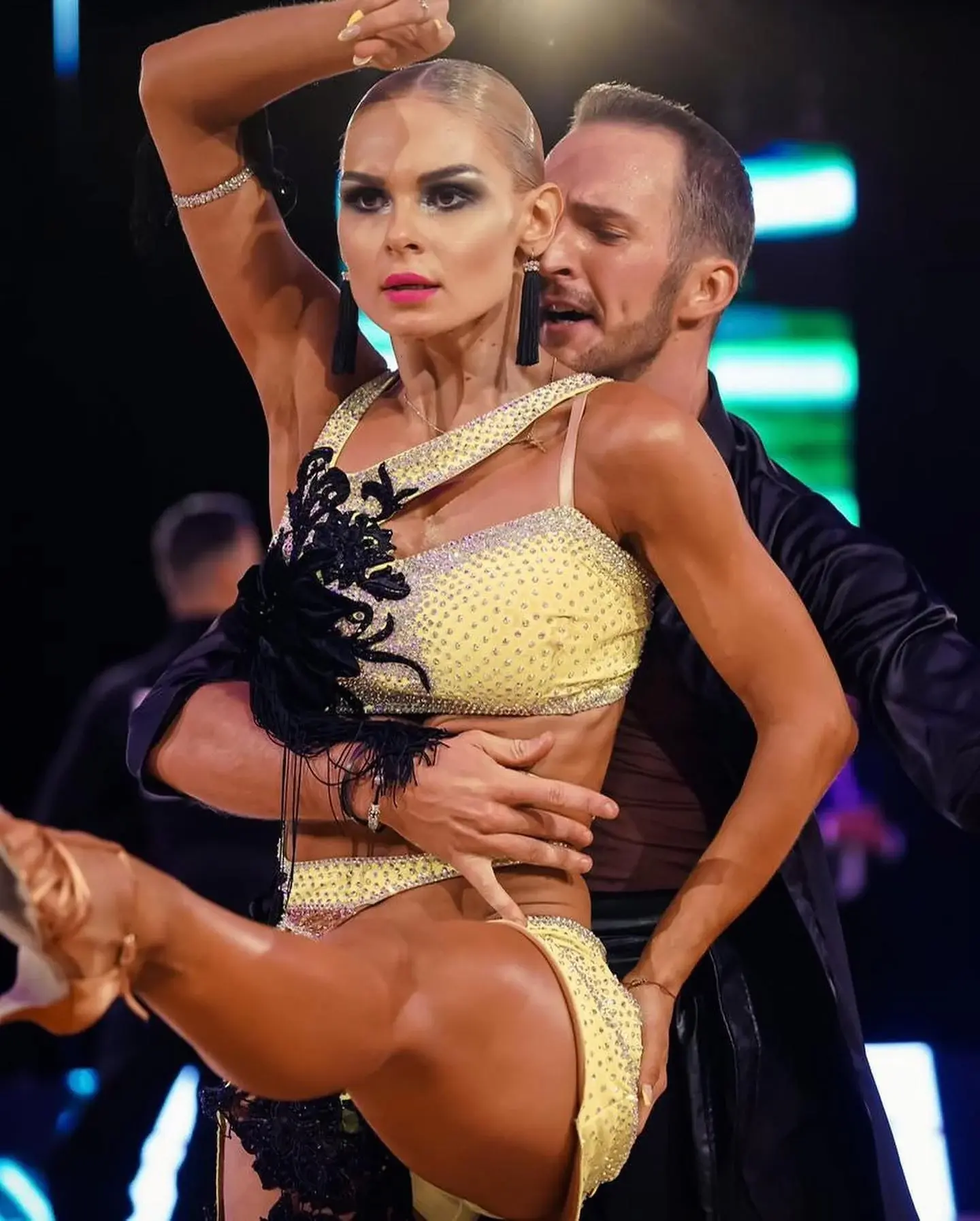 Tanečný pár v žltom a čiernom kostýme pri latinskoamerickom tanci